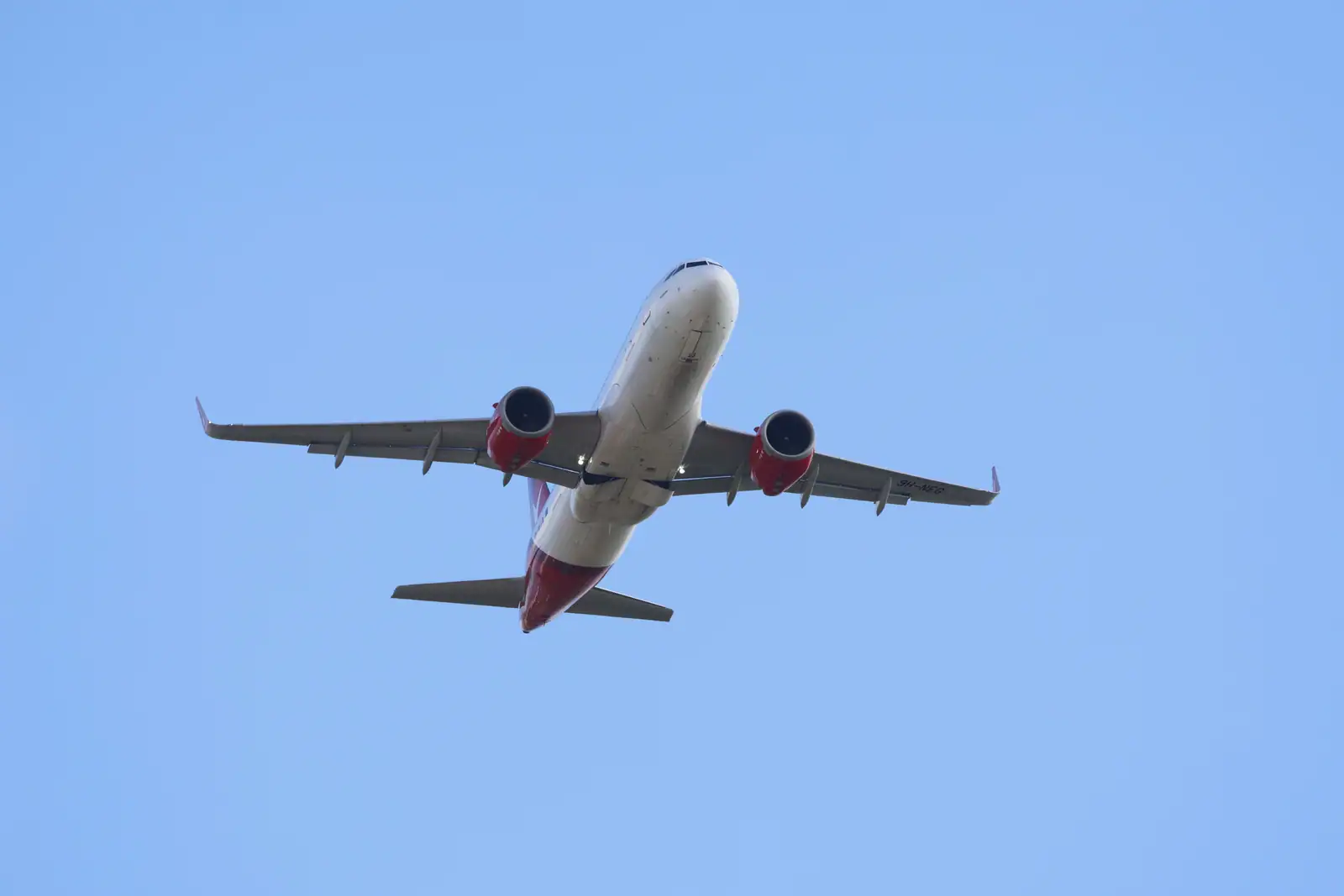 Avion de ligne en vol vu de dessous dans un ciel bleu dégagé