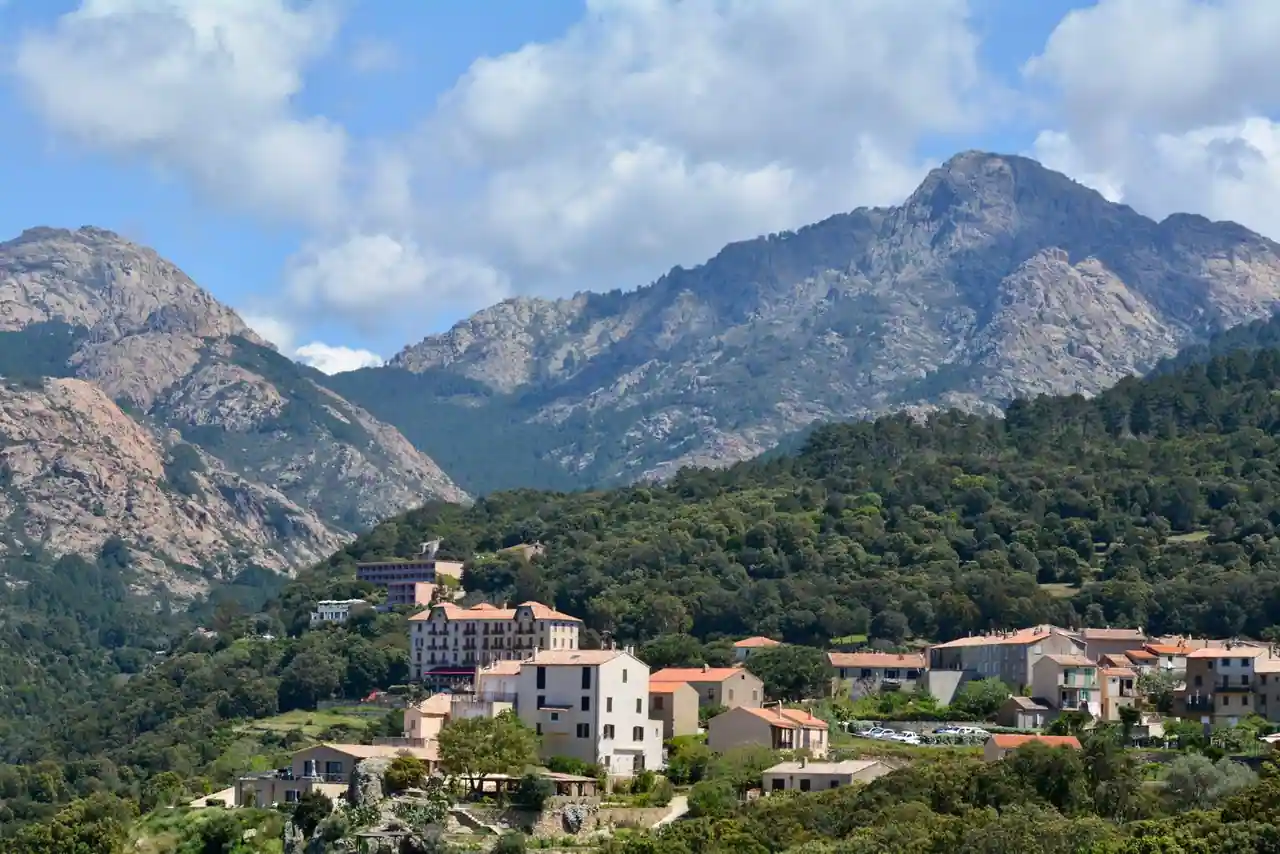 Village corse aux maisons de pierre et toits de tuiles, niché au creux d'une vallée de montagne