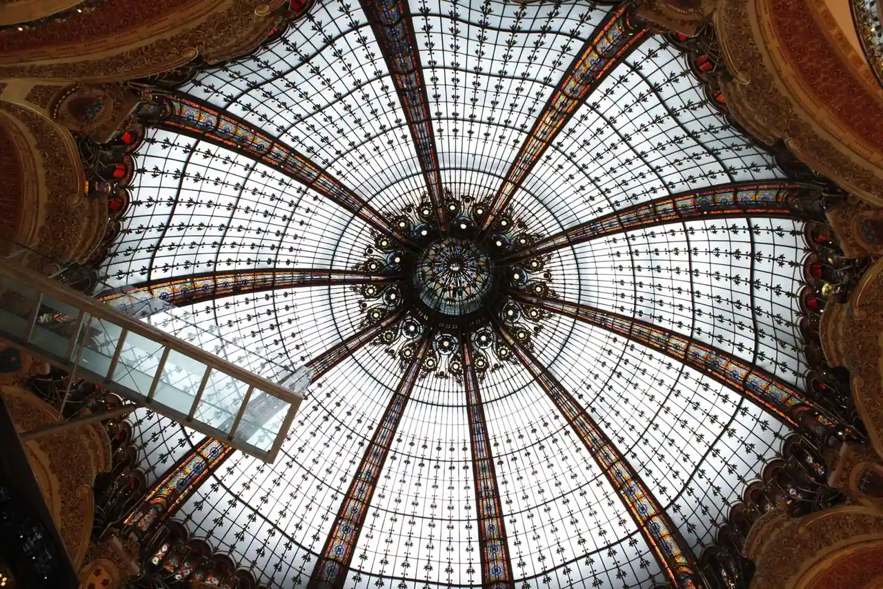Grande coupole de verre et de métal d'un édifice parisien historique, vue en contre-plongée