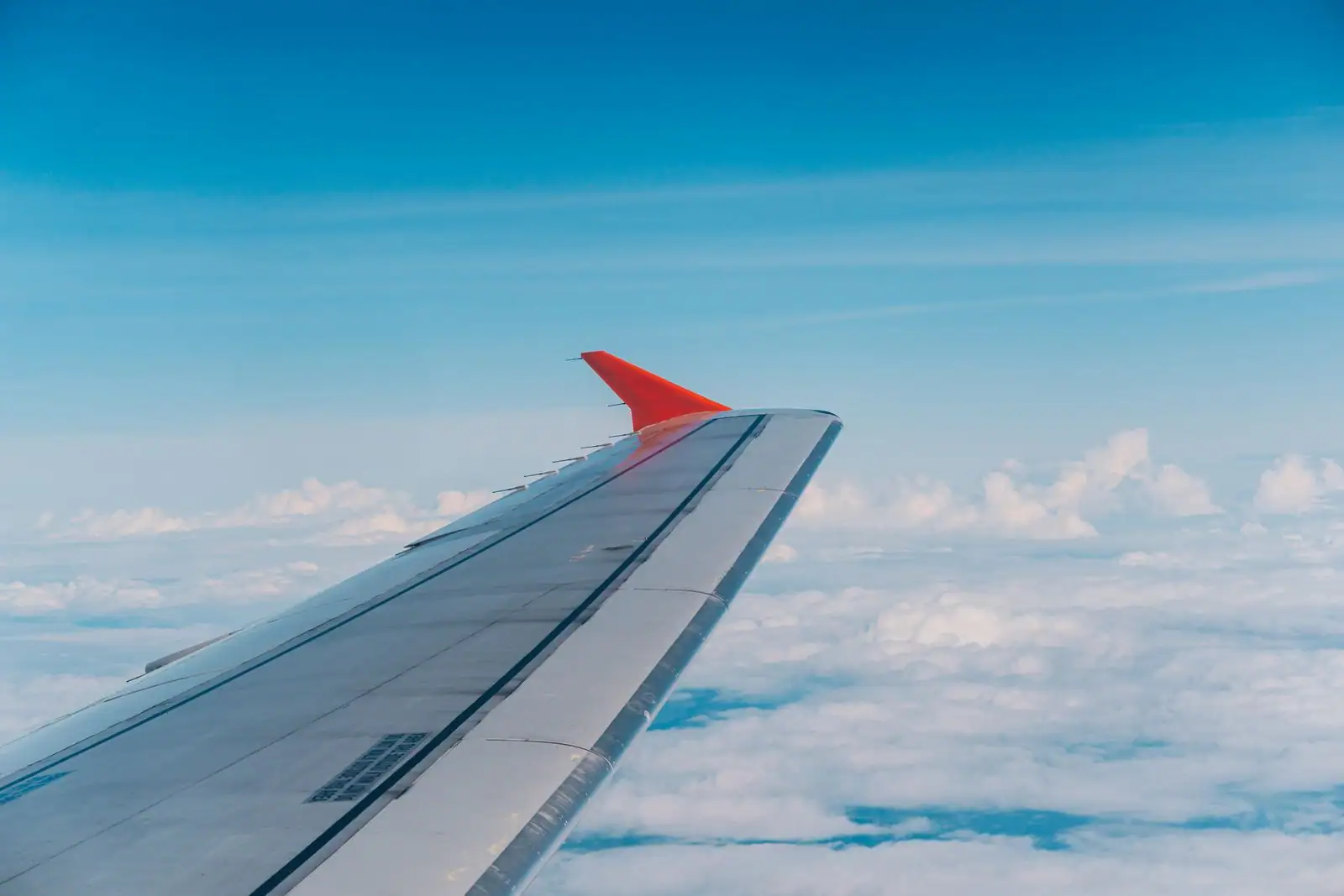 L'aile d'un avion de ligne en vol au-dessus des nuages.
