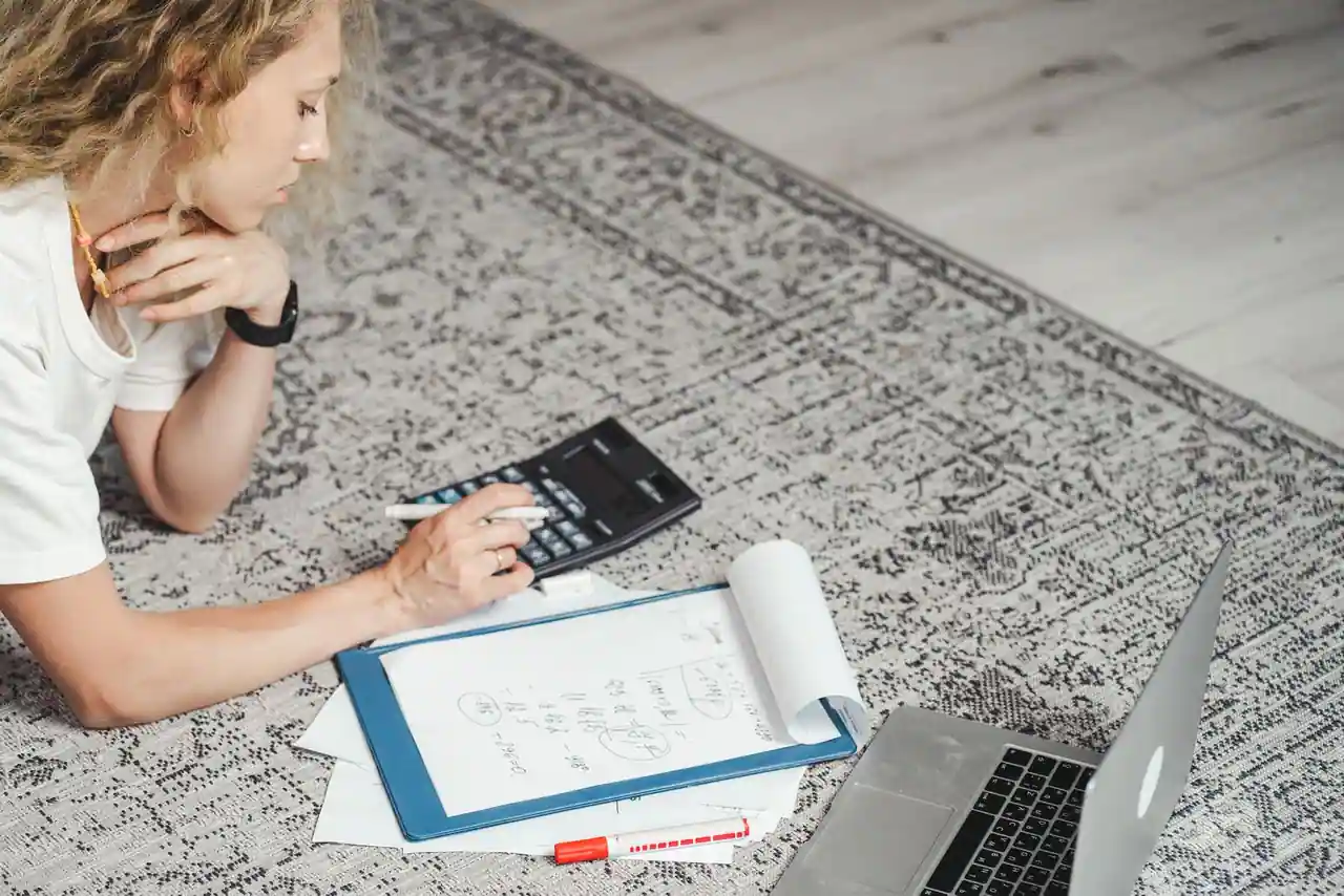 Freelance calculant son tarif journalier sur une calculatrice devant un ordinateur portable