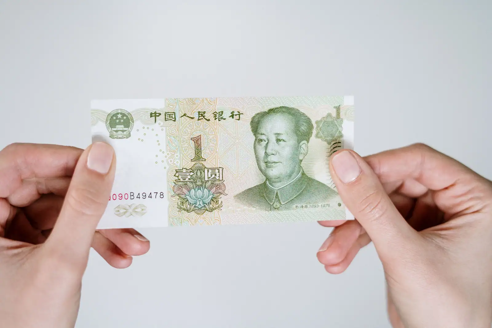 Mains tenant un billet de un yuan chinois, gros plan sur la devise chinoise à convertir en euros