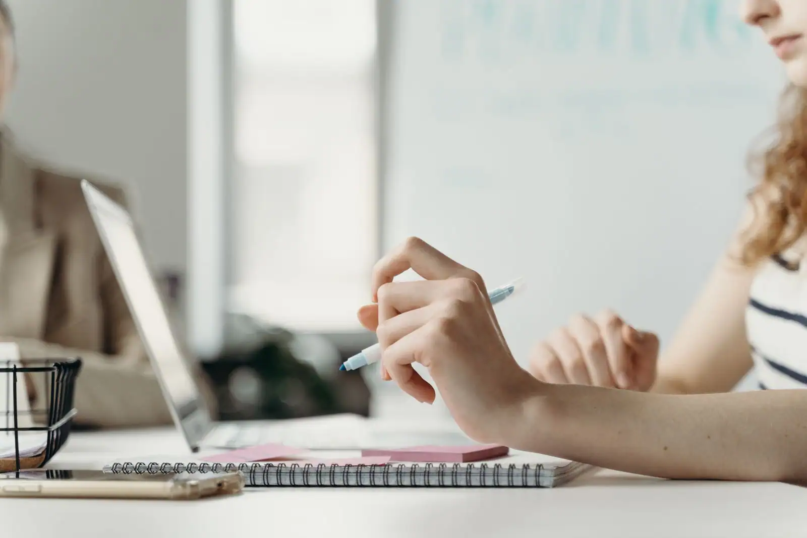 Deux personnes travaillent sur un projet professionnel avec un ordinateur portable et un carnet de notes.