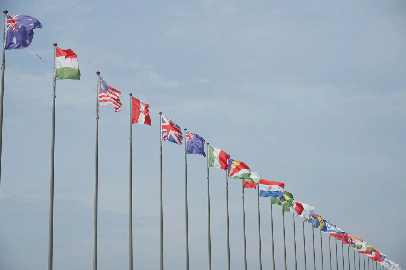Drapeaux de nombreux pays alignés sur des mâts, évoquant la coopération internationale