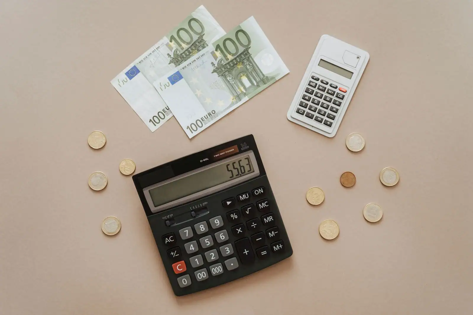 Calculatrice, billets et pièces en euros disposés sur un fond neutre pour un calcul financier.
