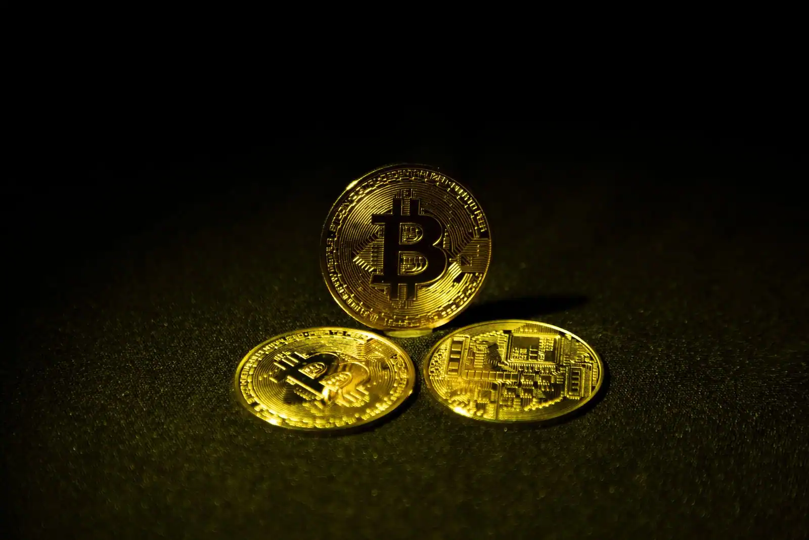 Pieces physiques representant des cryptomonnaies, posees en gros plan sur une surface sombre.
