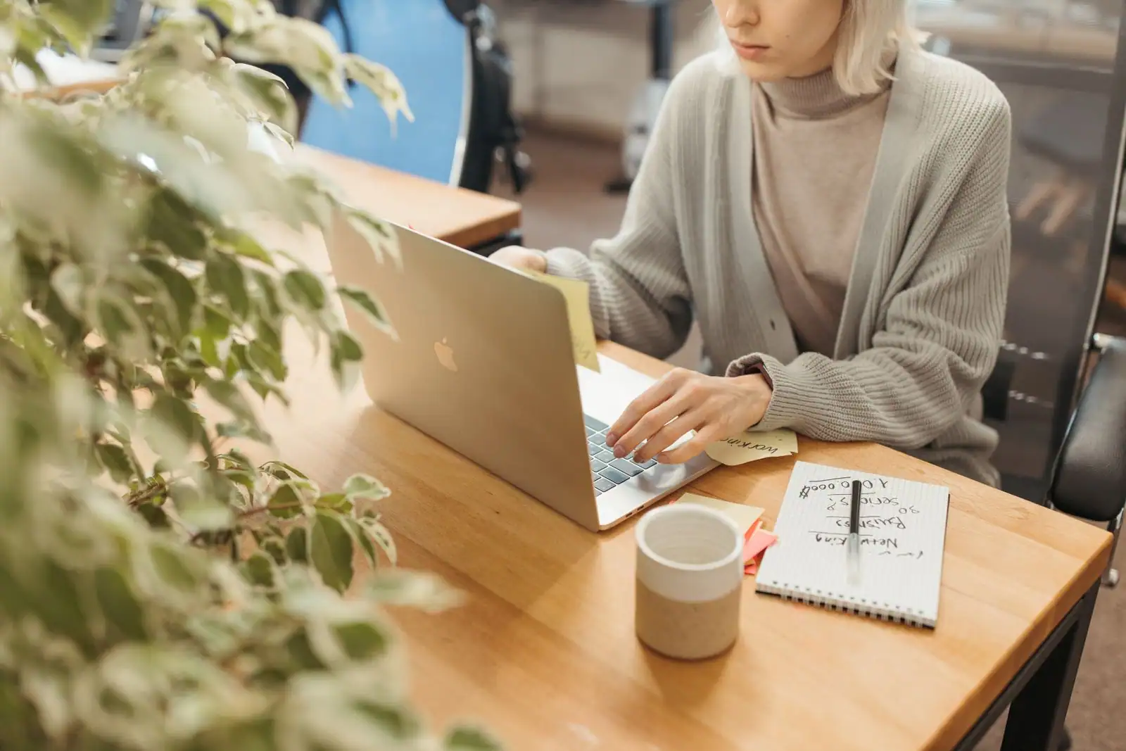 Personne travaillant sur un ordinateur portable à un bureau, dans un espace de travail lumineux.