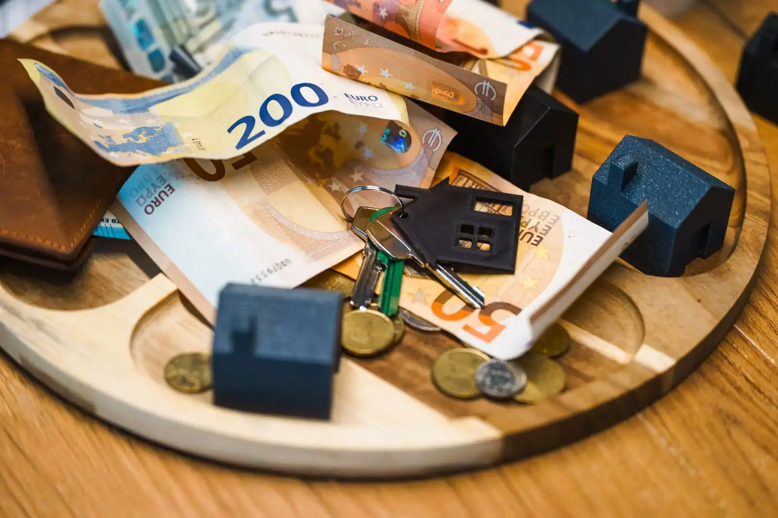 Maisons miniatures, clés et billets en euros évoquant l'épargne pour un projet immobilier