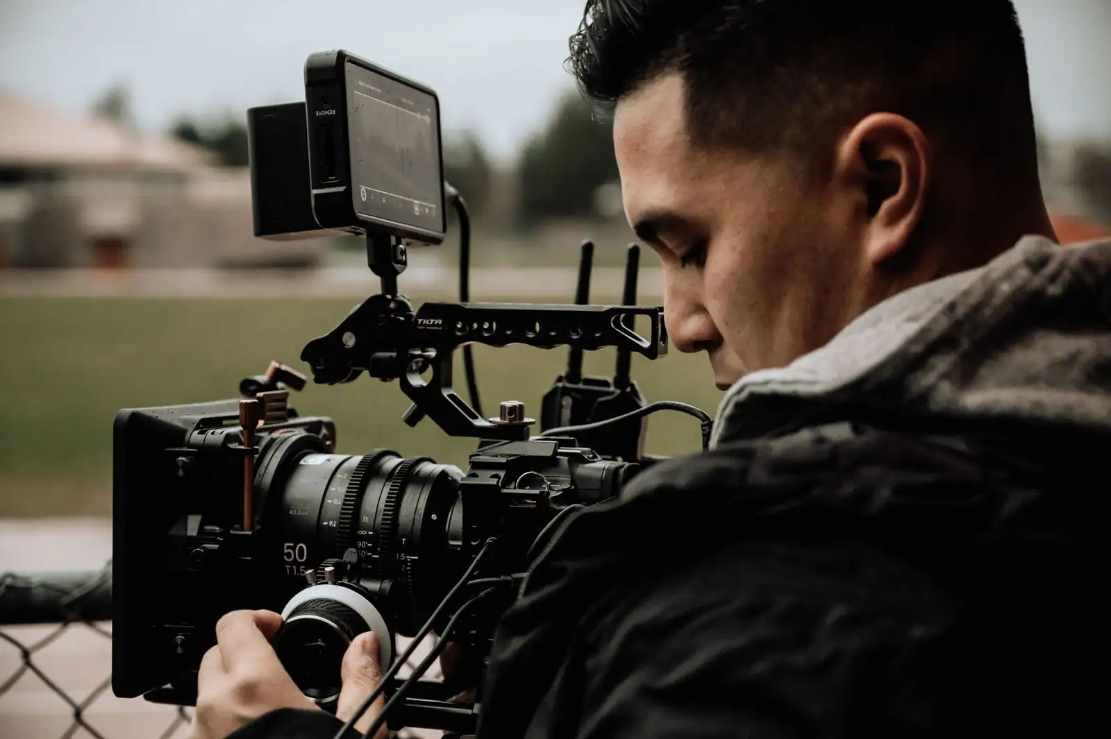 Cadreur cadrant avec une caméra de cinéma équipée d'un moniteur, en tournage extérieur.