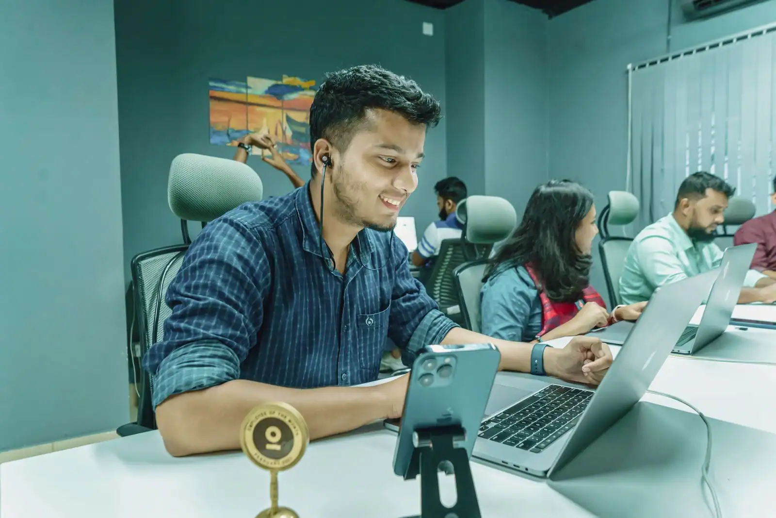 Jeune professionnel souriant travaillant sur un ordinateur portable à un bureau dans un espace de coworking