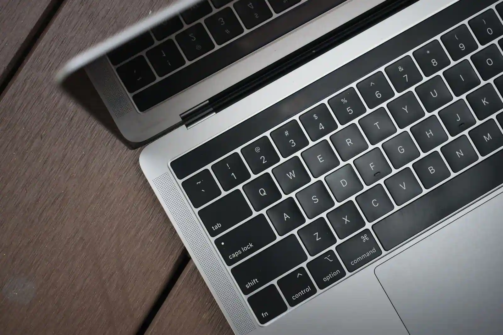 Le clavier ouvert d'un ordinateur portable argenté posé sur un bureau en bois
