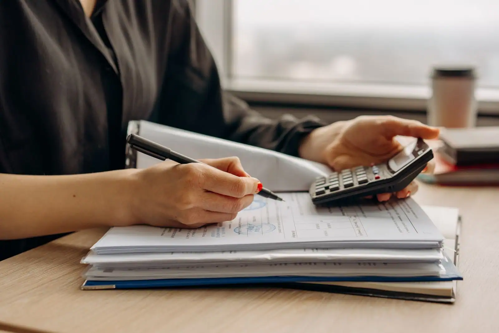 Personne traitant des documents administratifs avec une calculatrice et un stylo à un bureau