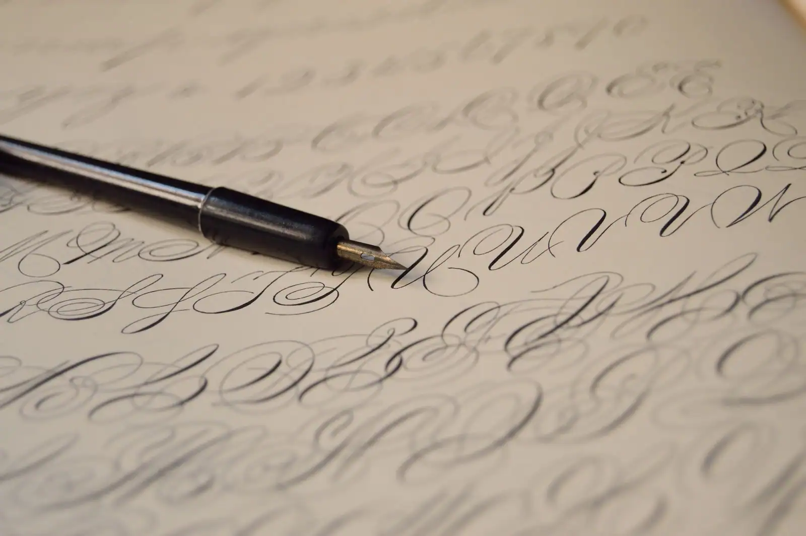 Porte-plume posé sur une feuille couverte d'écriture cursive à l'encre noire