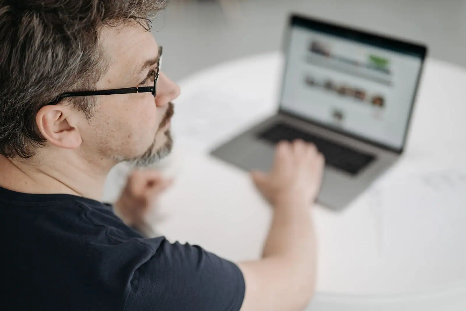 Un homme consulte des annonces sur un site web depuis l'écran de son ordinateur portable.