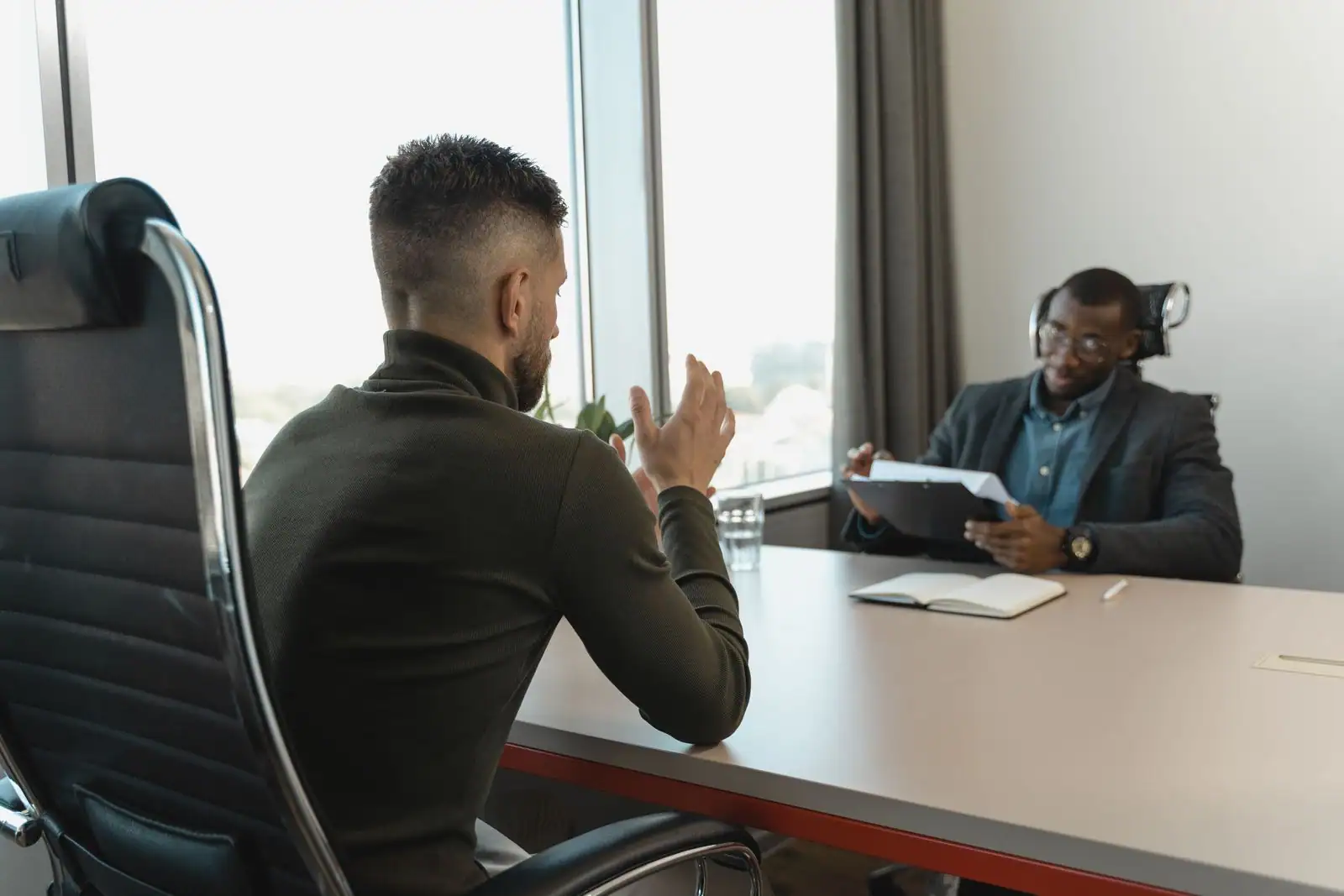 Entretien d'embauche dans un bureau, un candidat face à un recruteur qui consulte un dossier