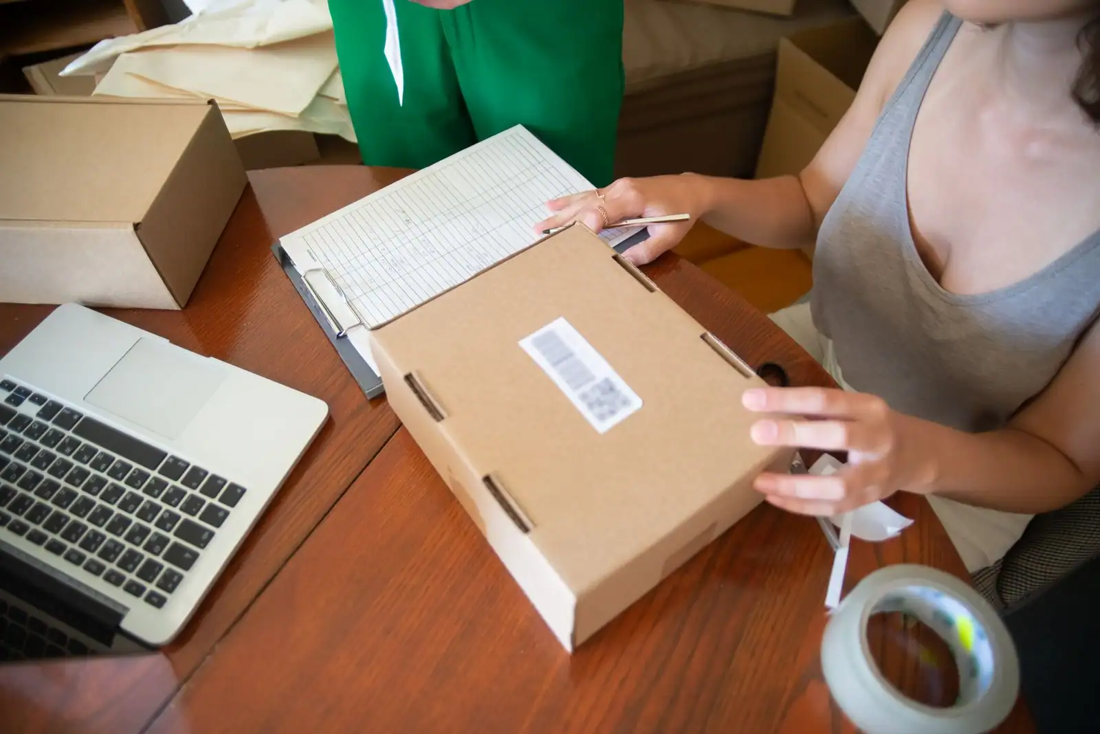 Vendeuse indépendante préparant et emballant une commande client sur son plan de travail