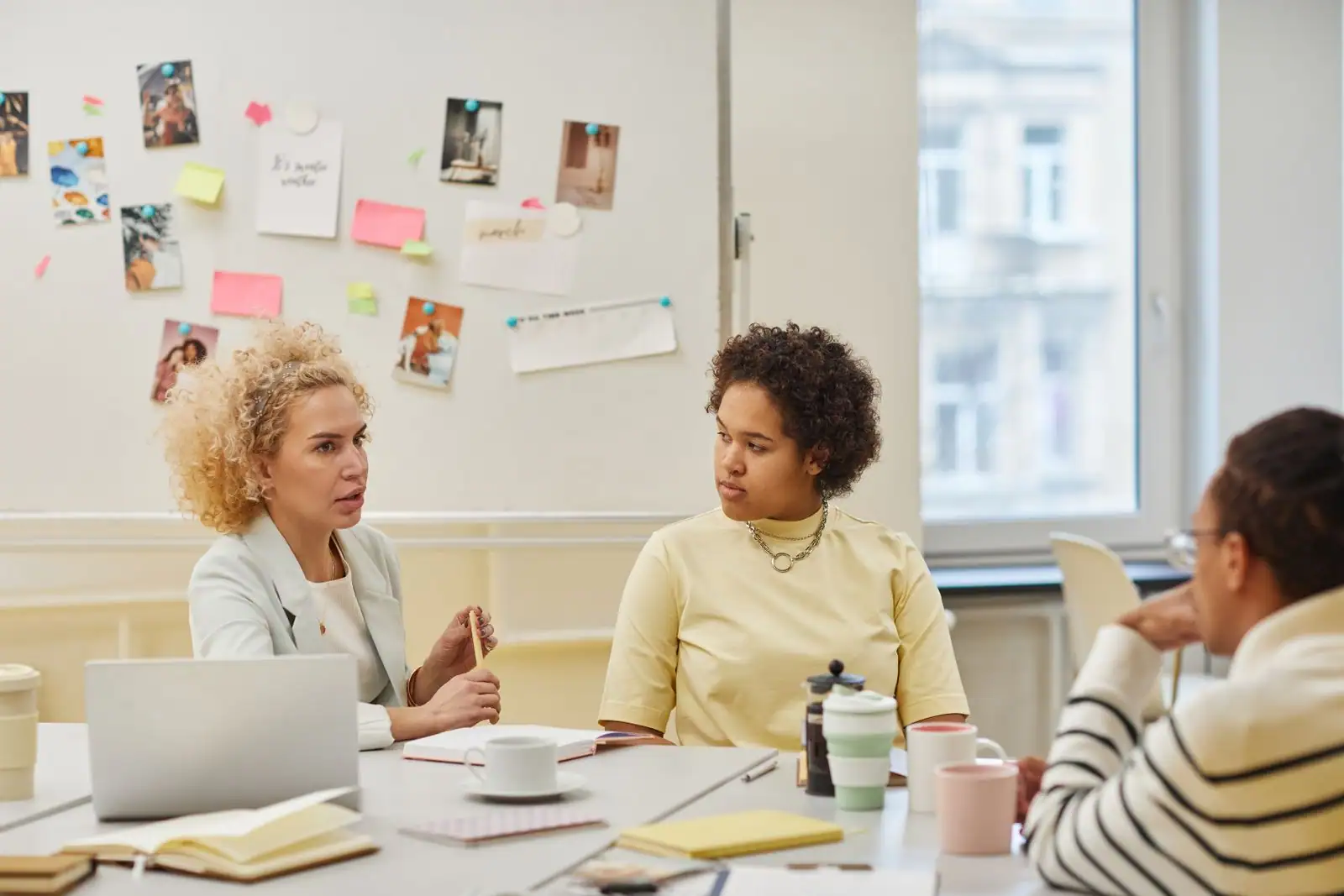 Équipe réunie autour d'une table de travail, en pleine discussion devant un tableau d'idées.