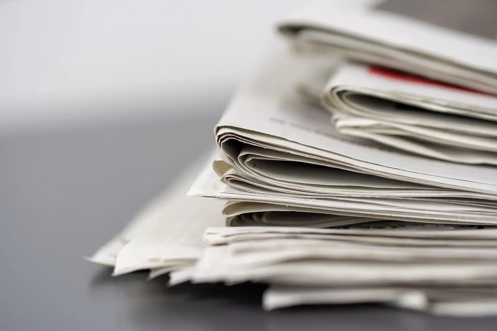 Plusieurs journaux empilés sur une table, évoquant le suivi quotidien de l'actualité internationale.