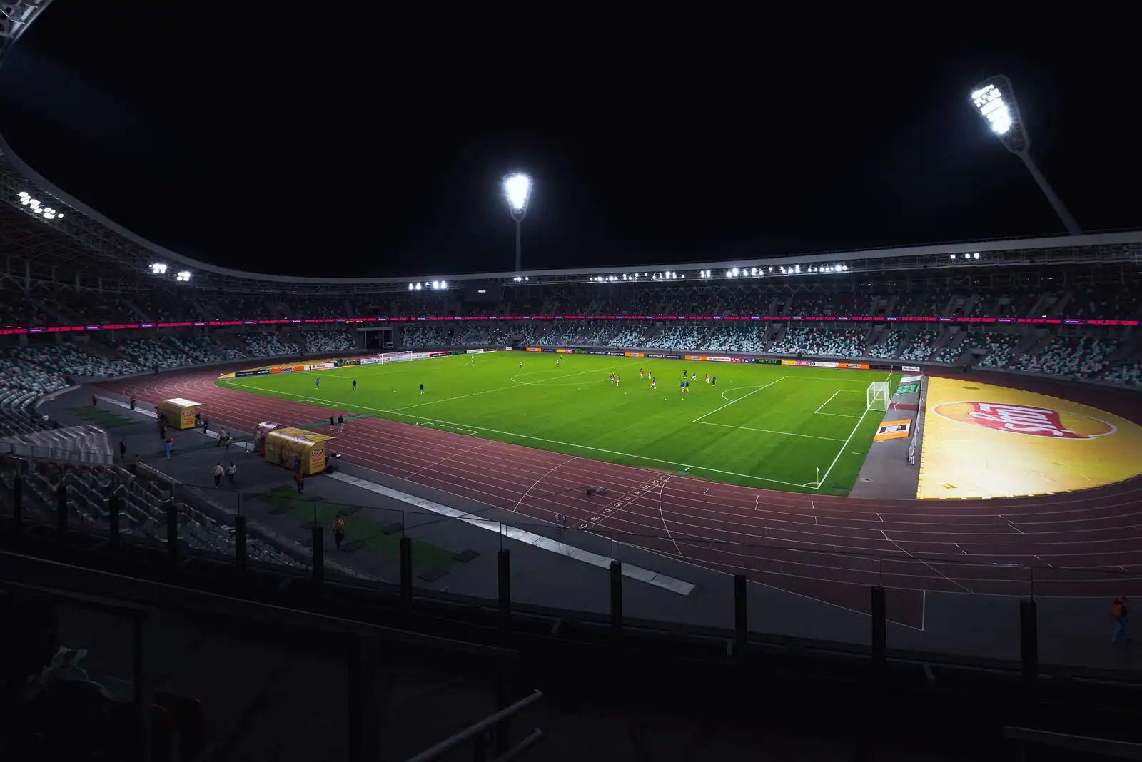 Tribunes d'un grand stade et pelouse verte éclairées avant une rencontre sportive