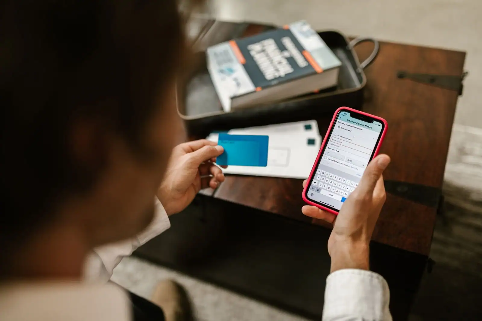 Personne tenant une carte bancaire bleue et saisissant un paiement sur son smartphone