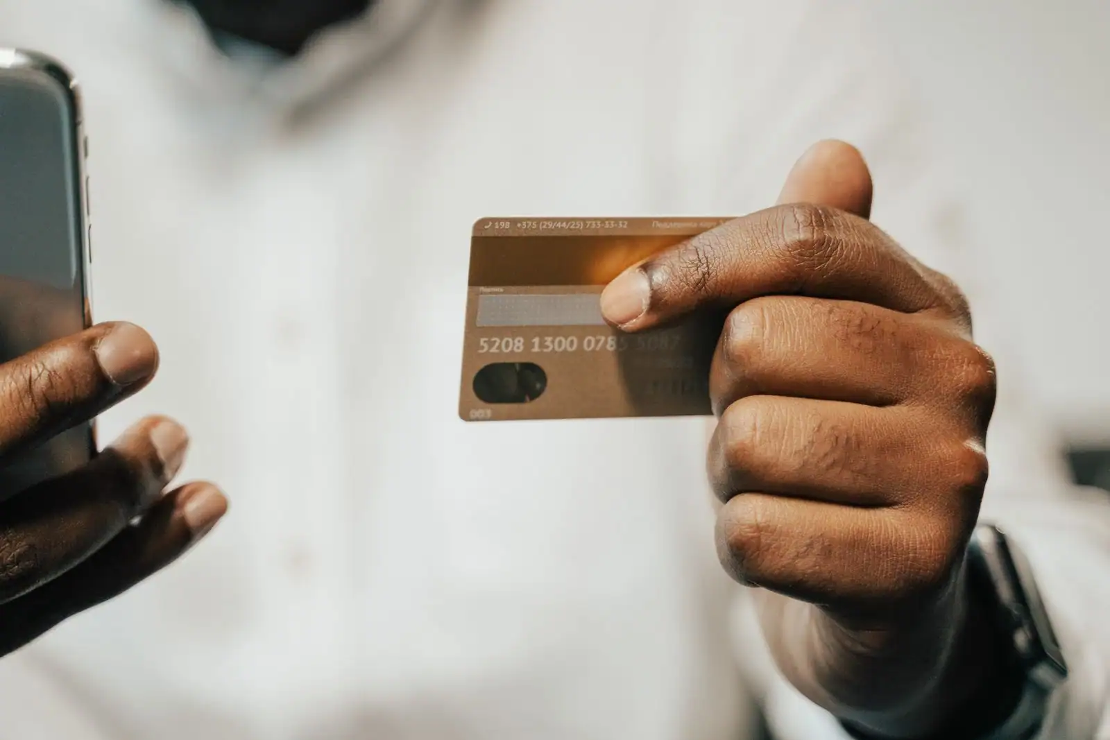 Personne tenant une carte bancaire dans une main et un smartphone de paiement dans l'autre.