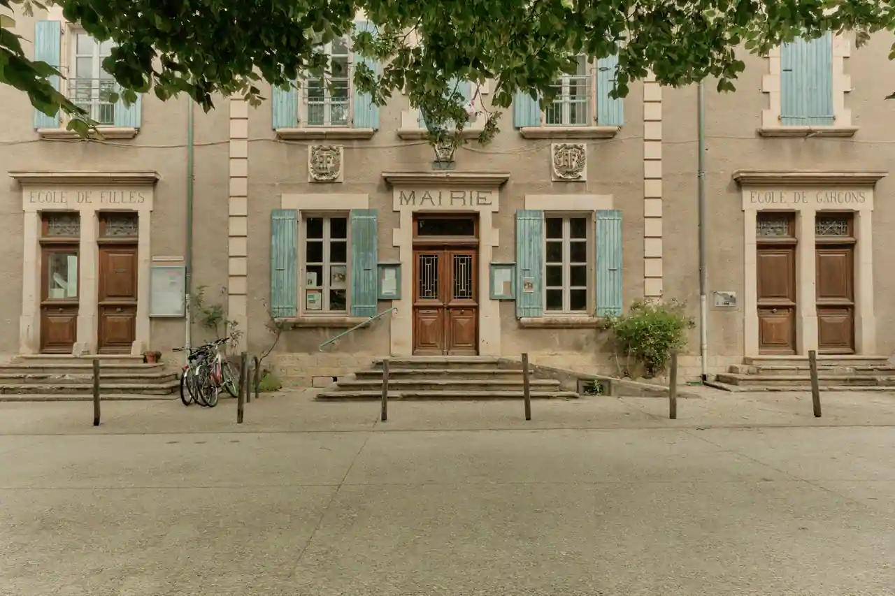 Façade d'une mairie de village française, avec ses vitrines d'affichage municipal et ses volets bleus.