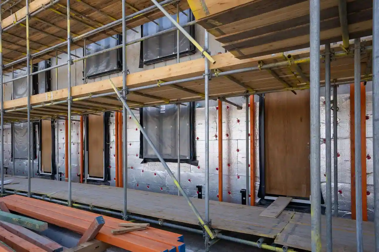 Façade d'un bâtiment d'habitation en chantier, isolation posée et échafaudage monté devant les ouvertures.