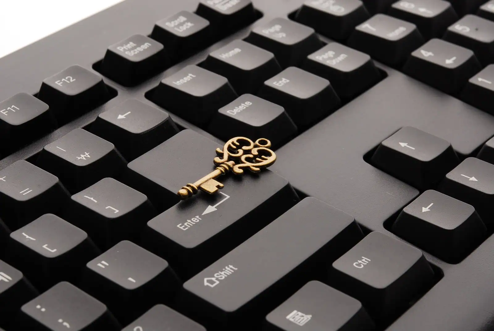 Petite clé ancienne en laiton posée sur la touche Entrée d'un clavier d'ordinateur noir