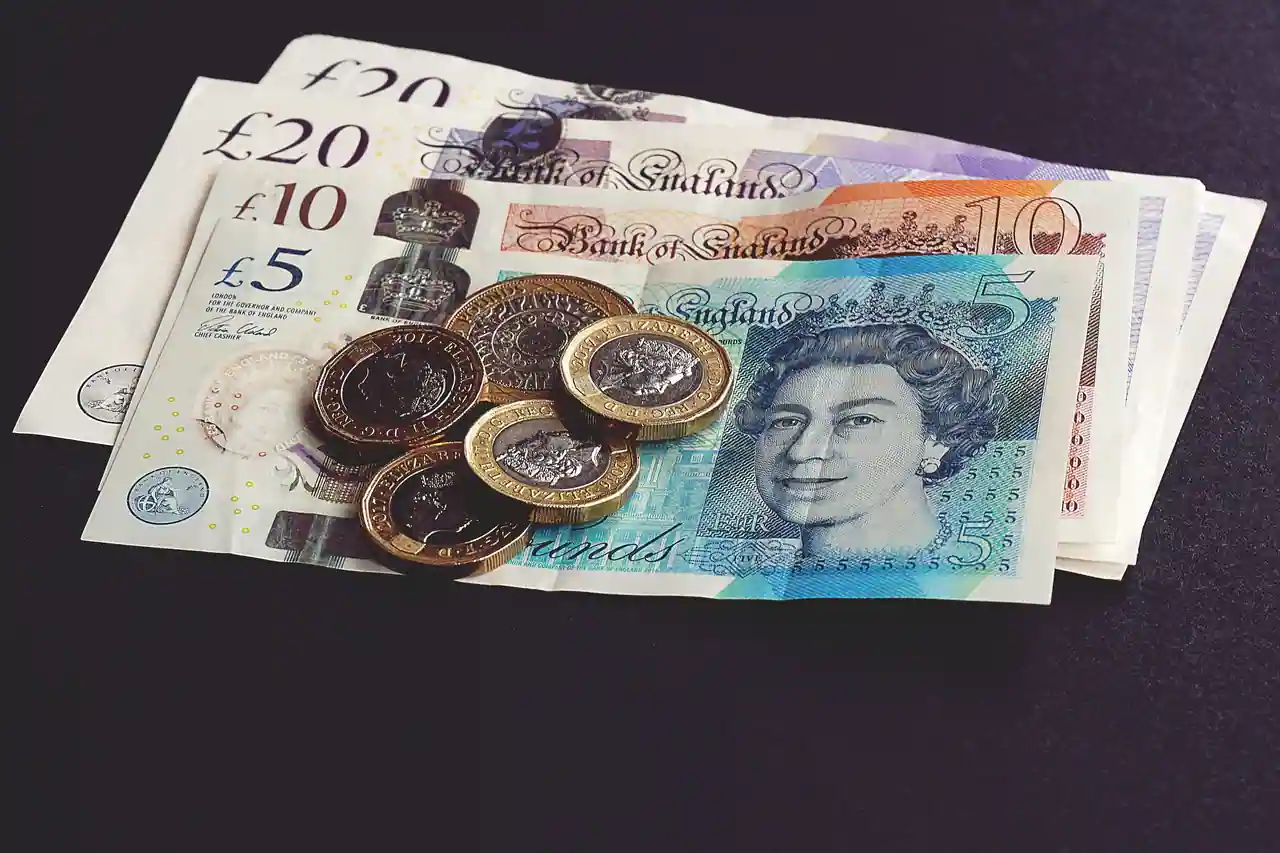 Billets et pièces en livres sterling posés sur une surface sombre, la monnaie du Royaume-Uni