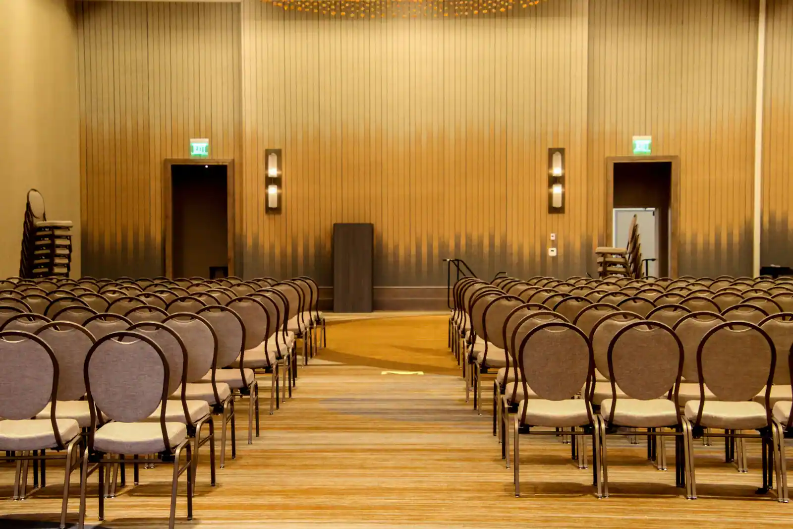 Rangées de chaises et pupitre dans une grande salle vide, préparée pour un événement d'entreprise
