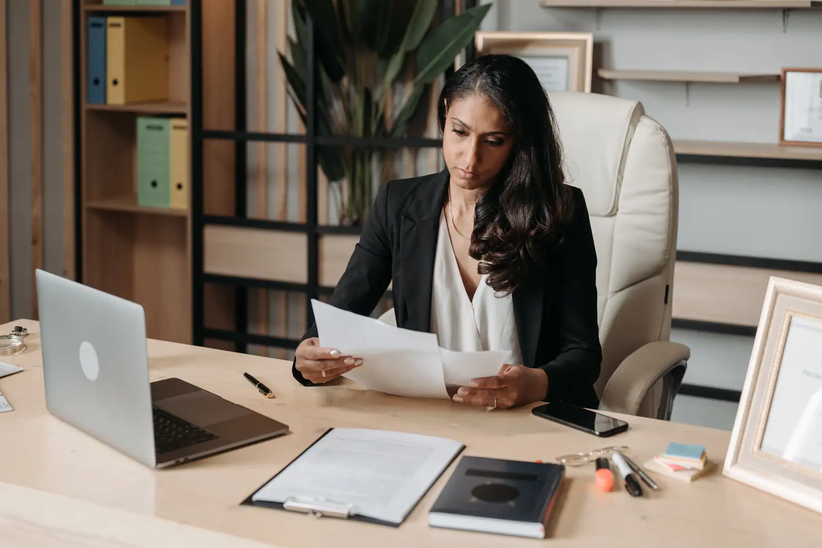 Relecture de documents imprimés à un bureau, avec ordinateur portable, porte-bloc et stylo à portée de main