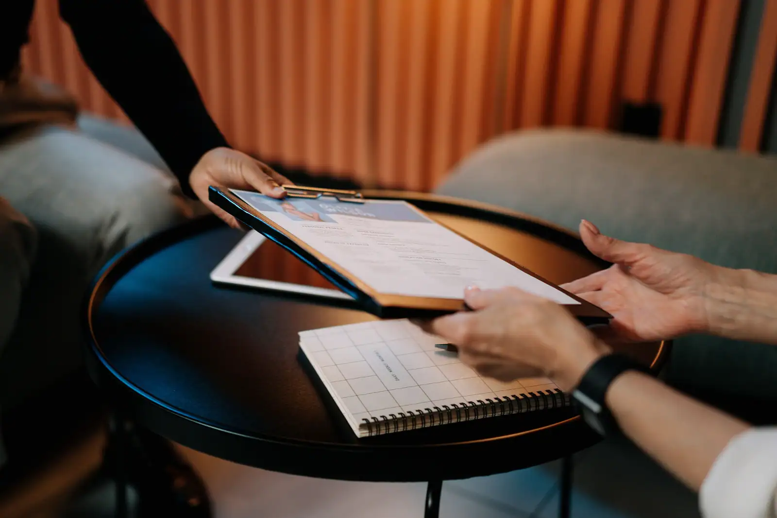 Curriculum vitae posé sur un porte-bloc, passé d'une main à l'autre au-dessus d'une table ronde.