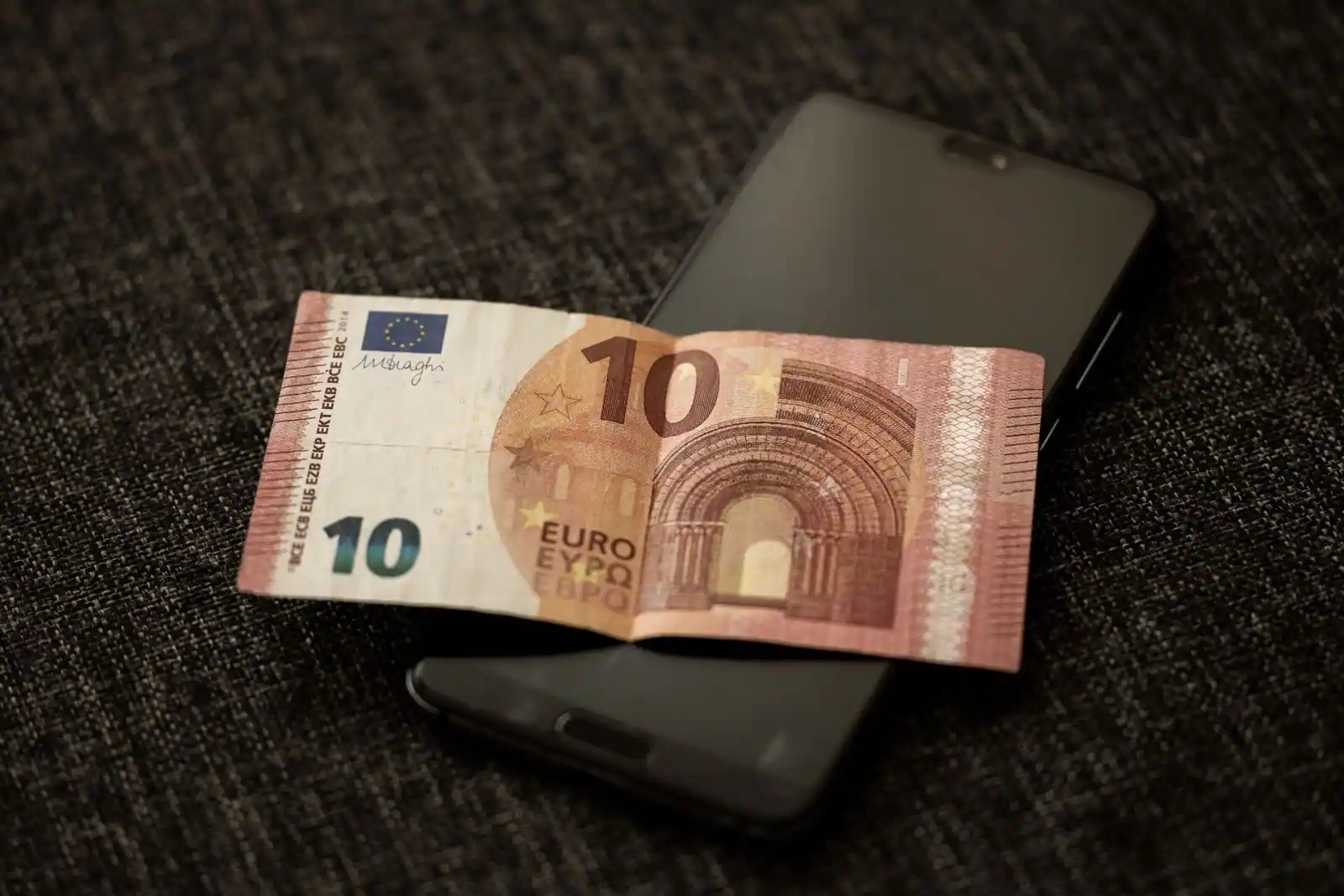 Billet de 10 euros posé sur un smartphone, symbole visuel de la conversion de devises numérique.