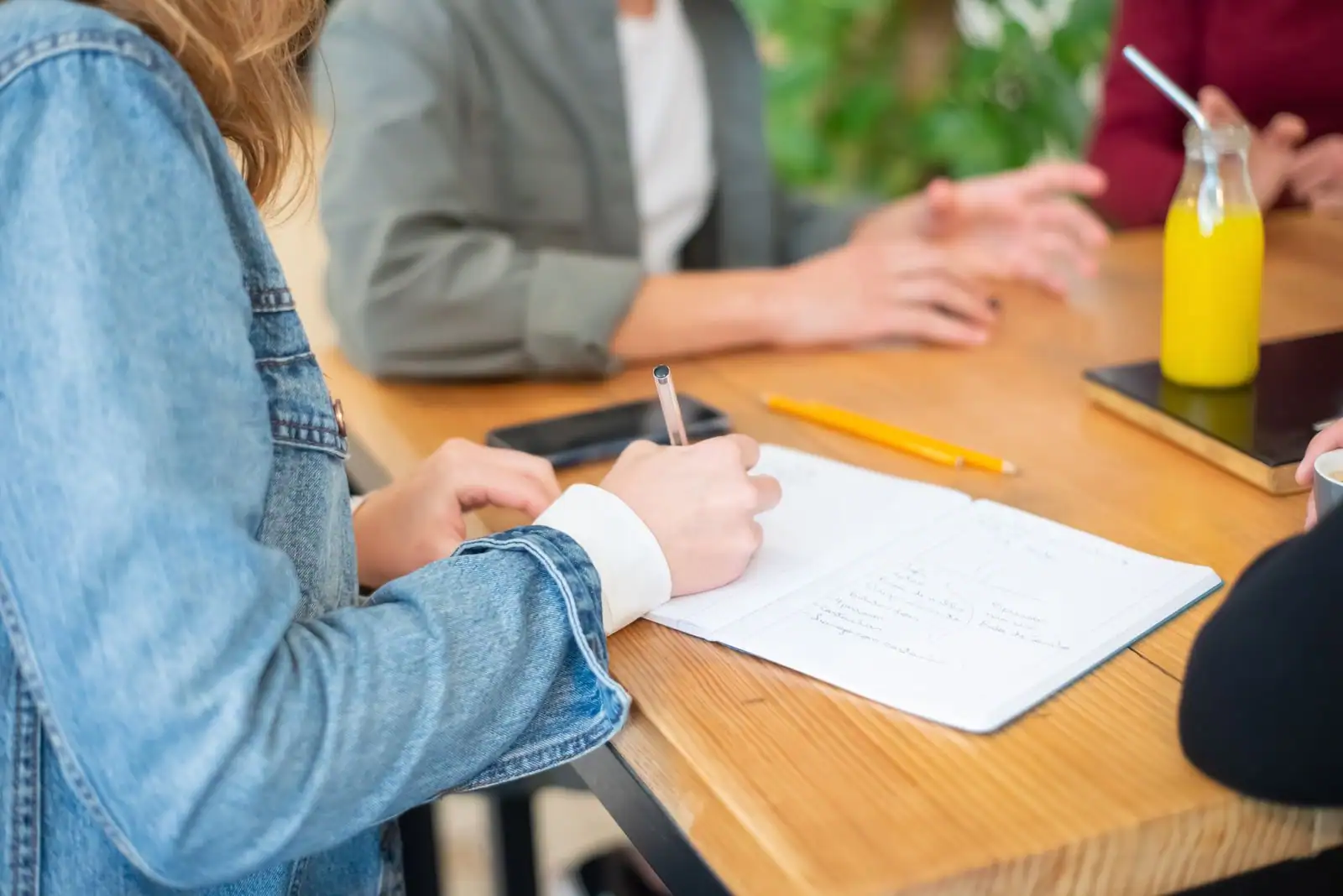 Petit groupe en formation professionnelle autour d'une table, prise de notes sur carnet